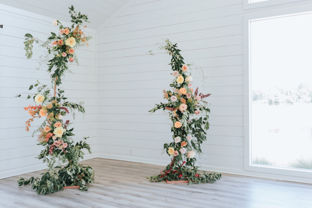 a gorgeous wedding floral installation in pastel colors of earth tones taken by joanna booth weddings at the farmhouse wedding event in houston texas